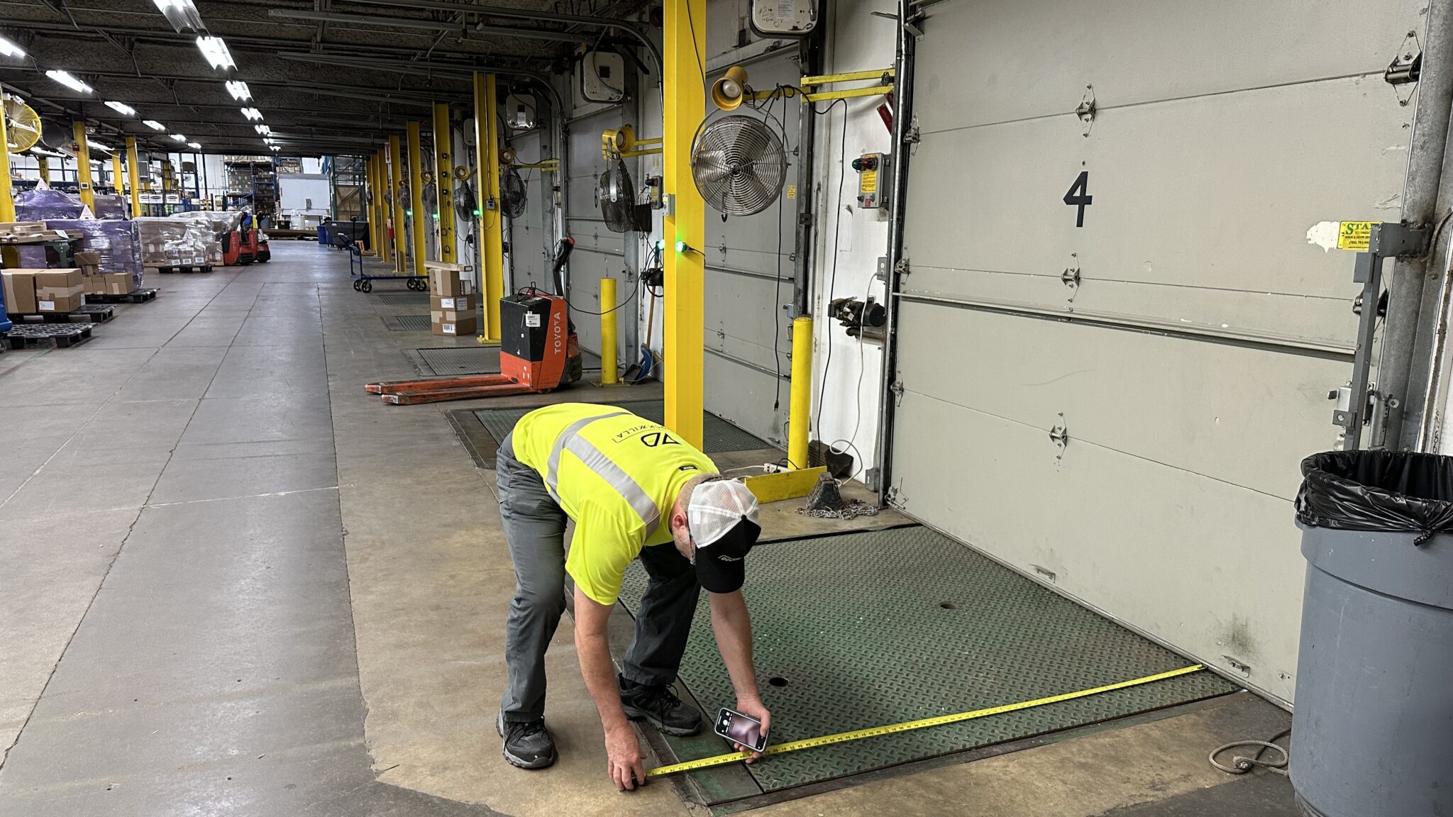 Employee measuring a in-floor loading dock pit leveler at a facility