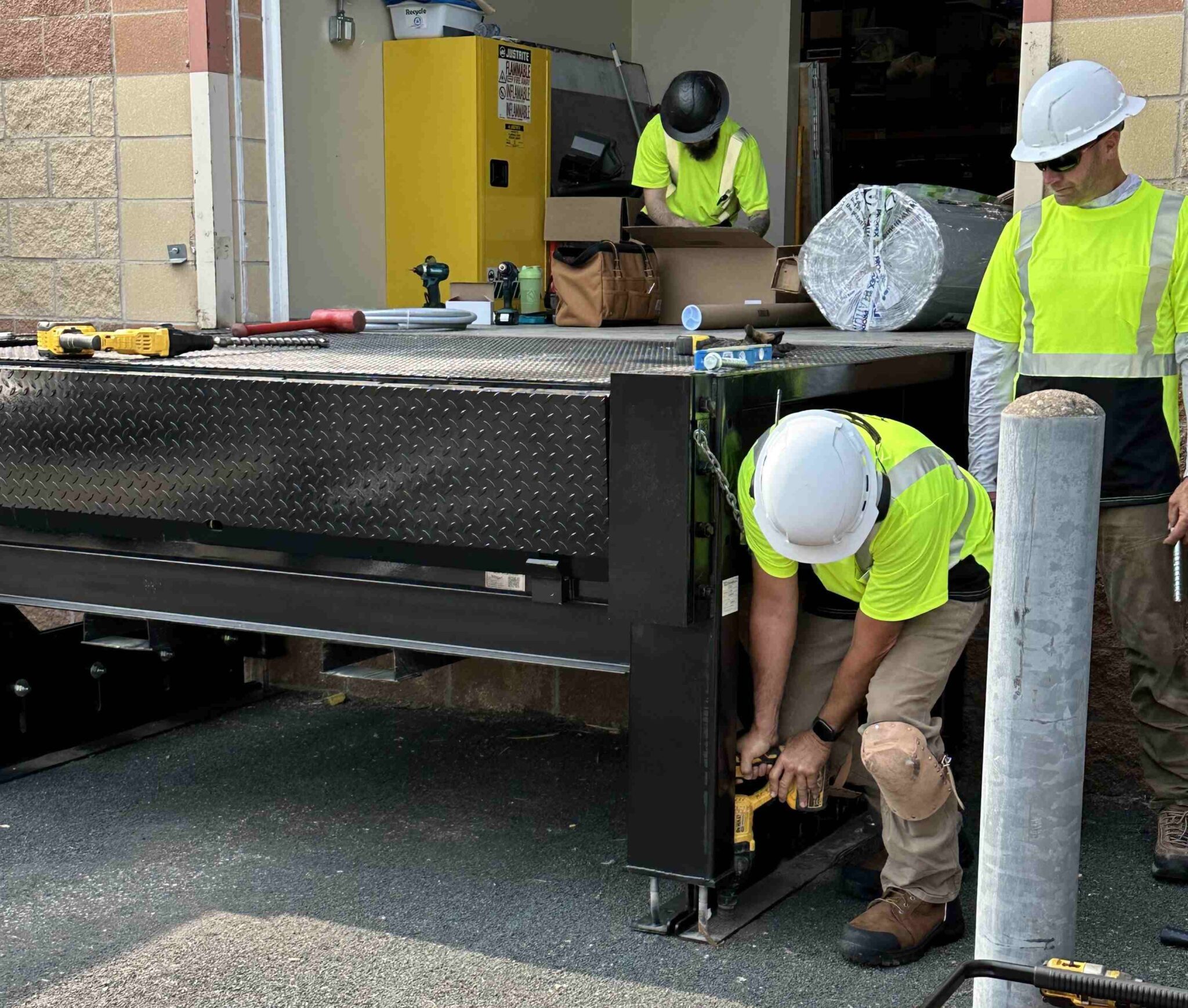 Workers bolt dock leveler frame to the ground